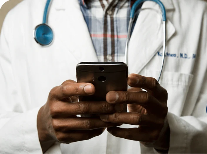 Médico de jaleco e estetoscópio consultando o celular