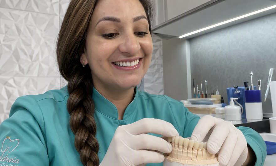Dra. Andréia Castro ajustando cuidadosamente uma prótese provisória sobre modelo de gesso