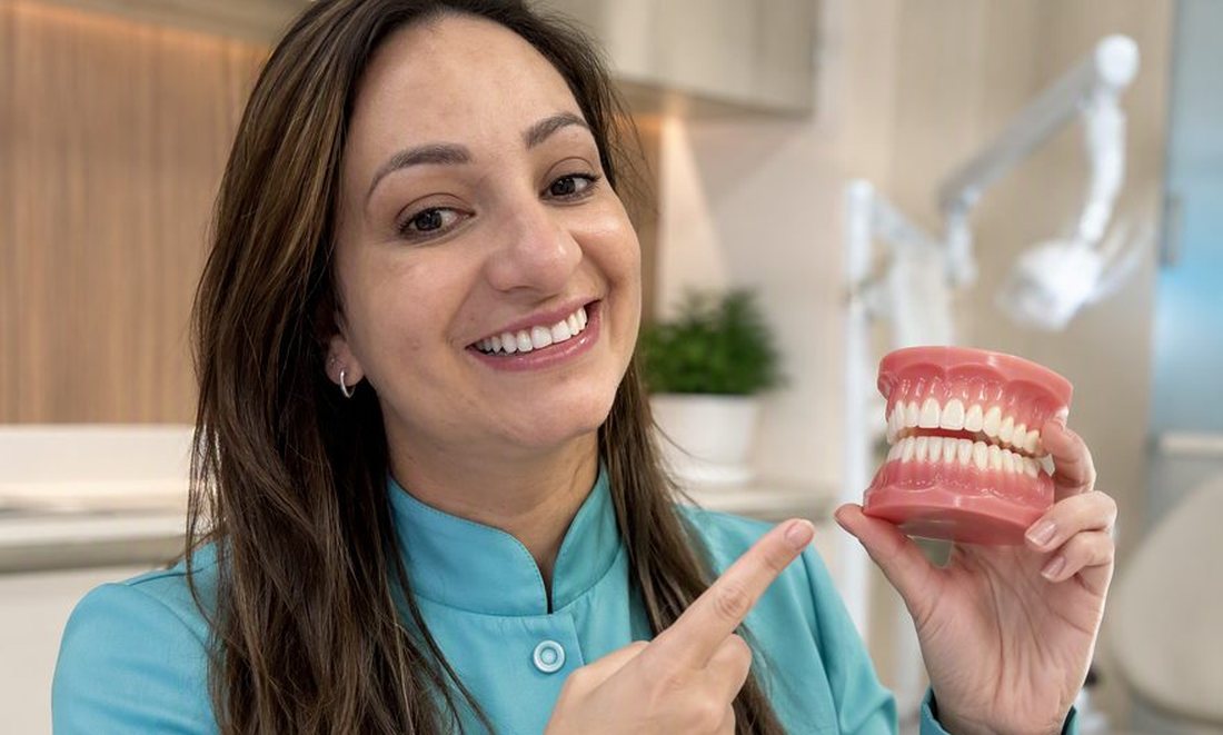 Dra. Andréia Castro segurando modelo de prótese total e explicando os tipos de prótese dentária